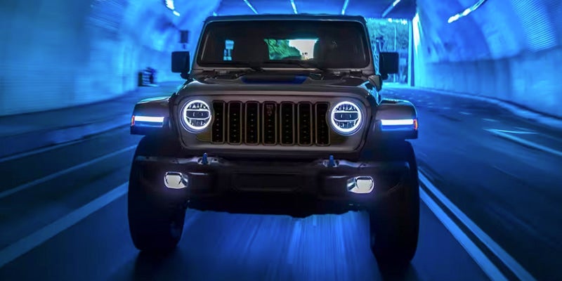 A photo of a 2024 Jeep Wrangler 4xe driving though a tunnel lit with blue lights