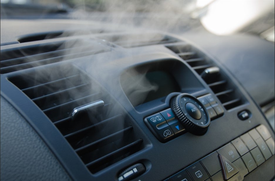 Car air conditioning vents blowing cool air from the dashboard climate control system.